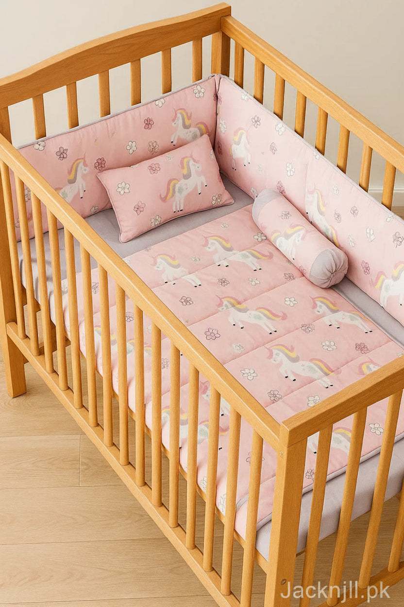 Unicorn printed baby crib bedding set in pastel colors with quilt, bumpers, and pillows arranged in a wooden cot.