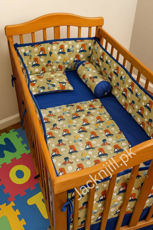 Olive-green and blue baby crib bedding set with colorful car prints, including quilt, bumpers, and pillows arranged in a wooden cot.